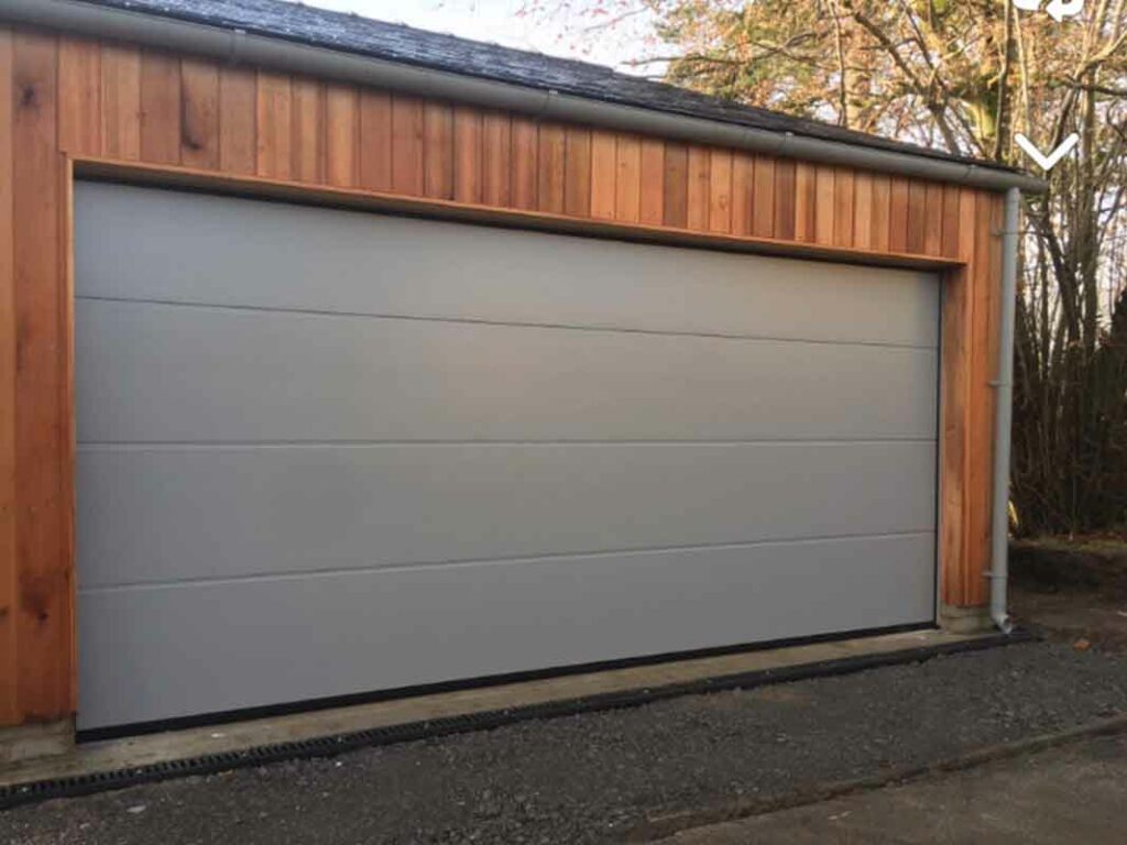 Light grey minimalist sectional garage door on a wooden facade