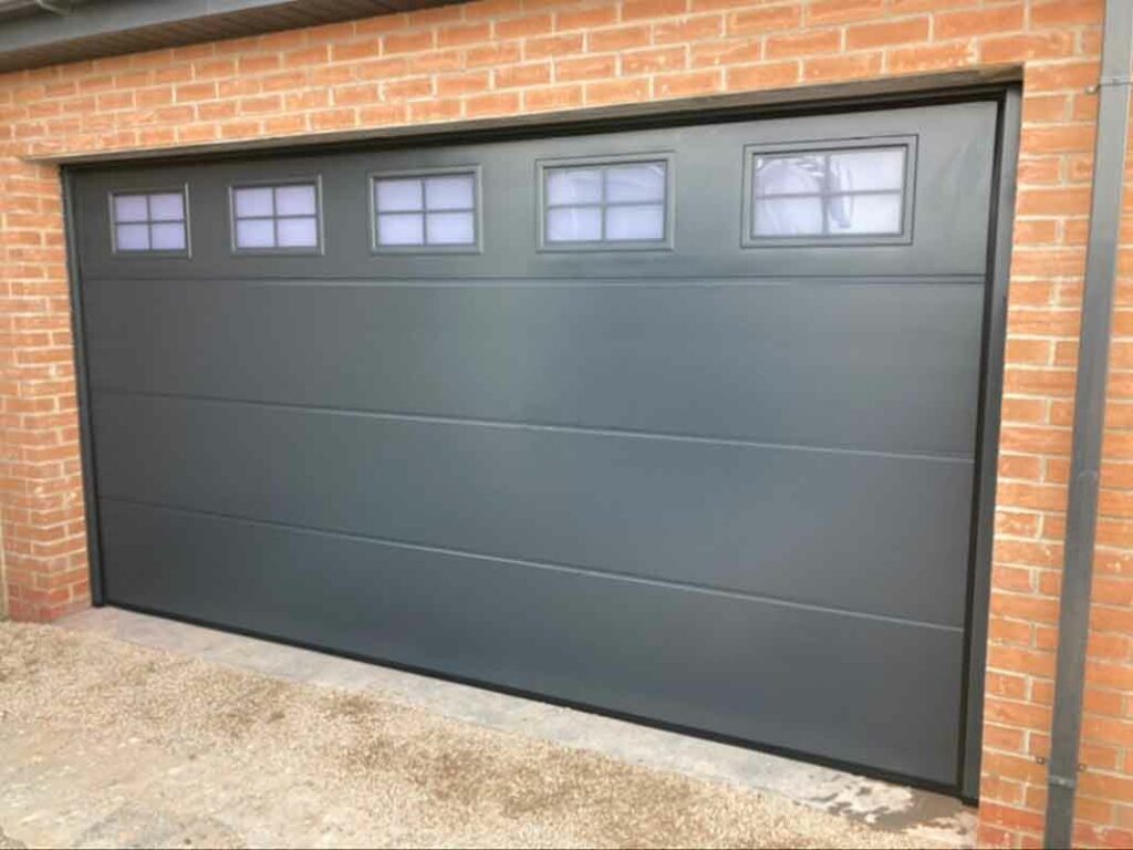 Charcoal grey sectional garage door with rectangular windows for a modern home