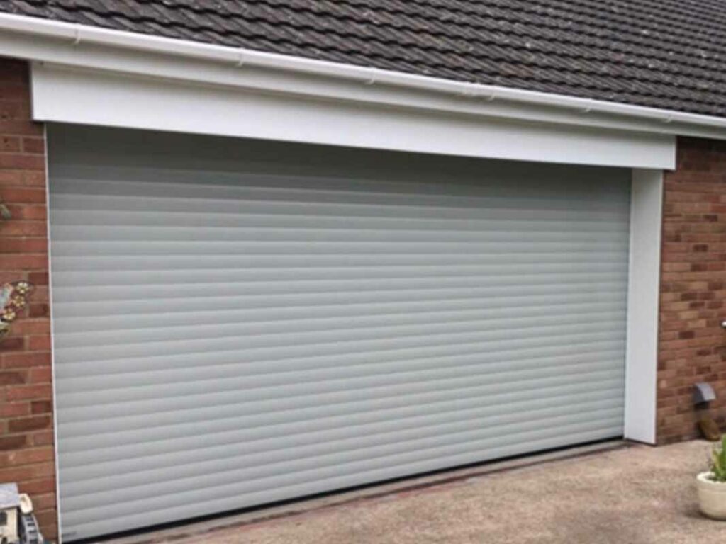 Light grey roller shutter garage door on a residential brick house